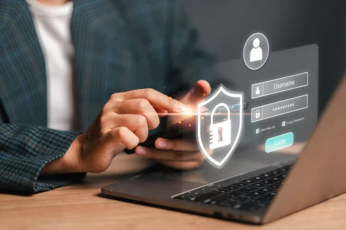 A modern login concept image featuring a hand interacting with a secure shield icon on a laptop screen, emphasizing user authentication and cybersecurity