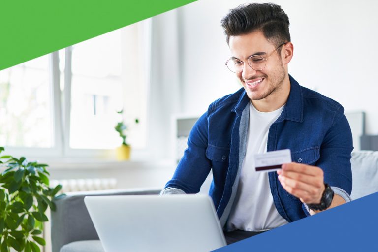 Male holding credit card looking at his laptop making a purchase