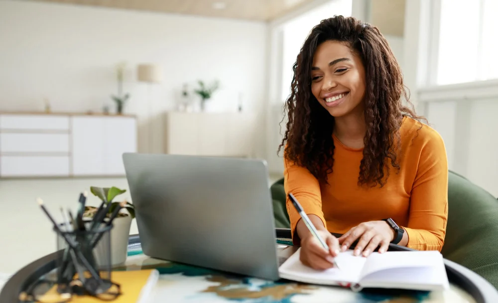 Woman sitting at desk working on laptop taking notes