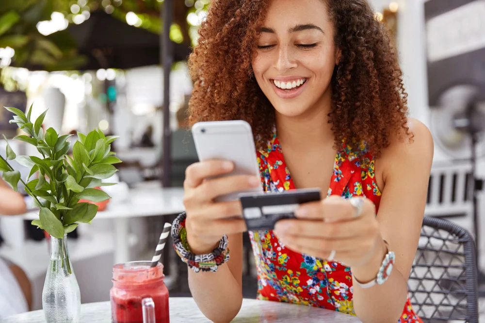 Woman holds smart phone and credit card banks online