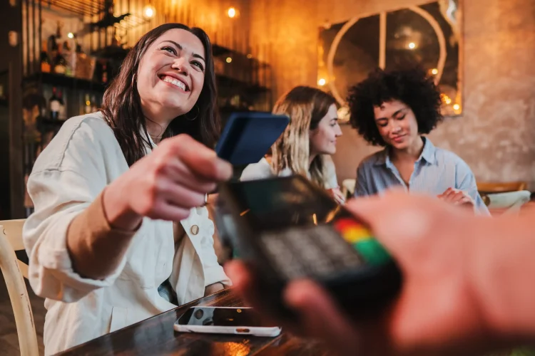 happy young woman paying bill with credit card in a restaurant