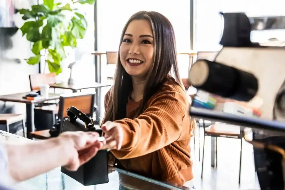 a barista handing a beverage to a customer at a cafe counter