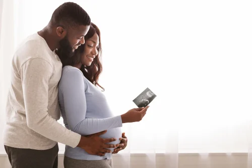 Emotional afro couple holding sonogram